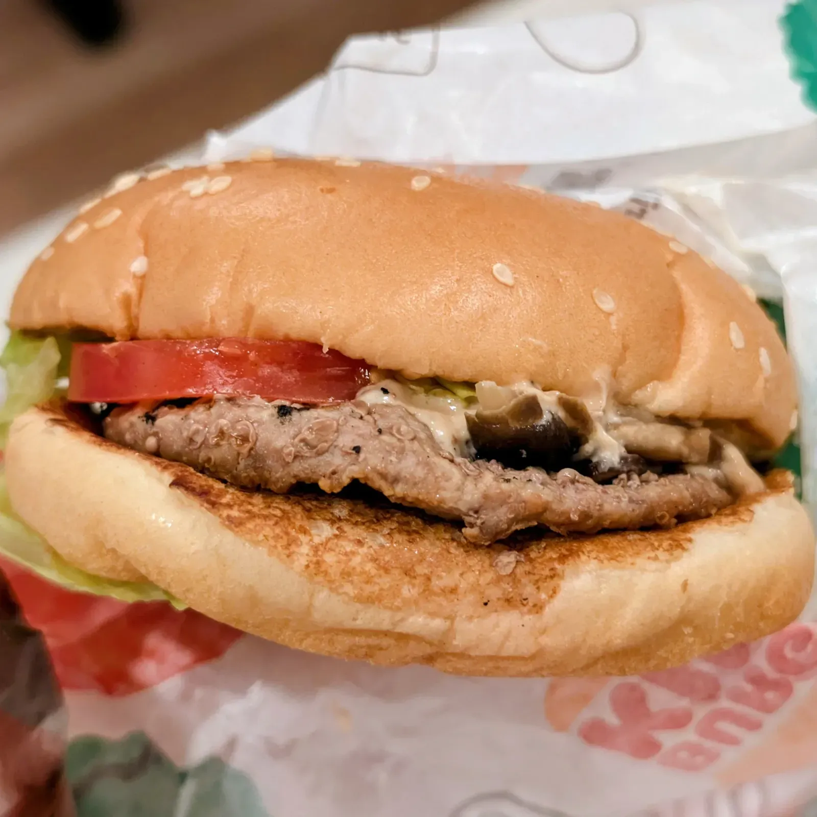持ち帰って夜に温め直したバーガーキングのマッシュルームワッパージュニア。パティの上にトマトとマッシュルームソース